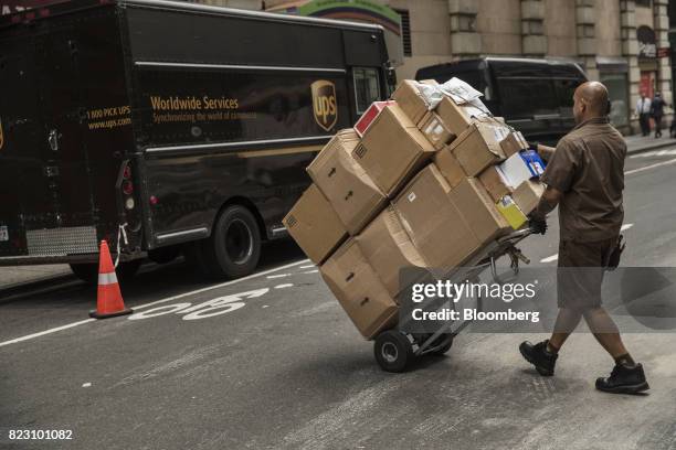 United Parcel Service Inc. Delivery driver pushes a dolly of packages towards a delivery van on a street in New York, U.S, on Monday, July 24, 2017....
