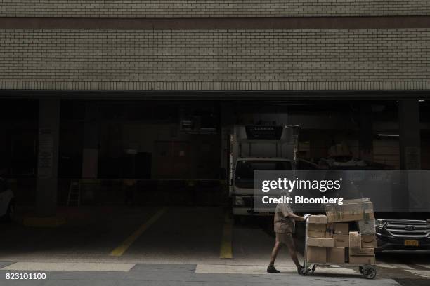United Parcel Service Inc. Delivery driver pushes a dolly of packages to be delivered along a sidewalk in New York, U.S, on Monday, July 24, 2017....