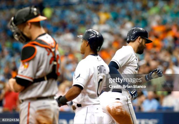 Evan Longoria of the Tampa Bay Rays celebrates with teammate Mallex Smith in front of catcher Caleb Joseph of the Baltimore Orioles after hitting a...