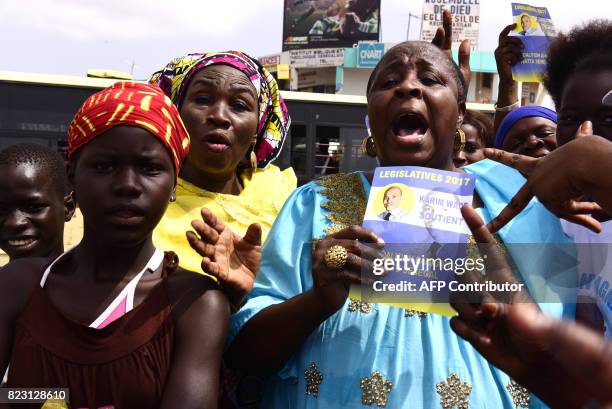 Supporters of Wattu Senegal coalition candidate and former president Abdoulaye Wade shout slogans while holding campaign flyers of his son Karim Wade...