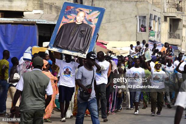 Supporters of Wattu Senegal coalition candidate and former president Abdoulaye Wade shout slogans while holding a portrait of his son Karim Wade...