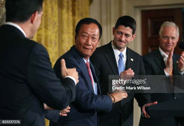 Terry Gou , chairman of Apple supplier Foxconn, shakes hands with Wisconsin Gov. Scott Walker as House Speaker Paul Ryan looks on at news conference...