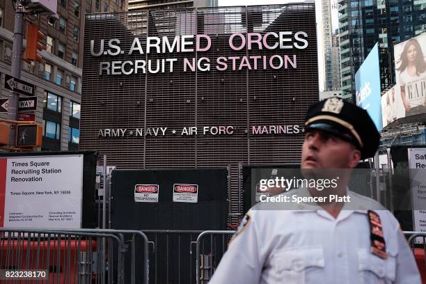 Police officer stands guard as dozens of protesters gather in Times Square near a military recruitment center to show their anger at President Donald...