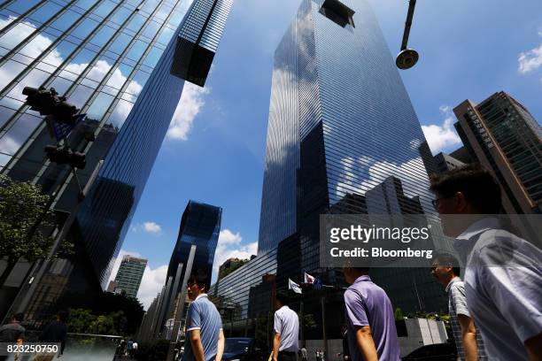 Pedestrians cross a road in front of the Samsung Electronics Co. Seocho office building in Seoul, South Korea, on Tuesday, July 25, 2017. Samsung...