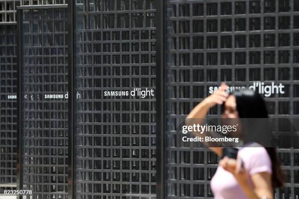 Pedestrian walks past Samsung Electronics Co. Signage outside the company's Seocho office building in Seoul, South Korea, on Tuesday, July 25, 2017....