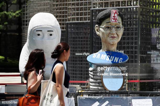 Pedestrians walk past the an effigy of Jay Y. Lee, co-vice chairman of Samsung Electronics Co., outside the Samsung Seocho office building in Seoul,...