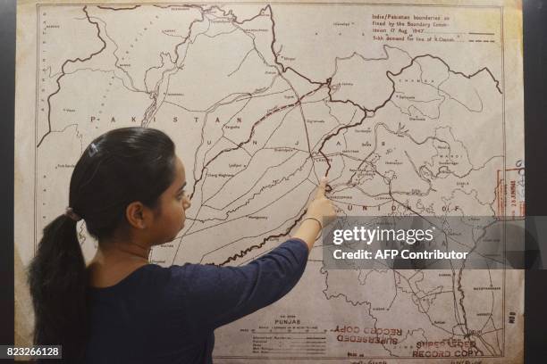 This photo taken on June 14, 2017 shows an Indian woman looking at a map of the India-Pakistan boundaries as fixed by the boundary commission on...