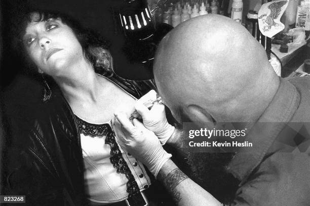 Tattoo artist, Bald Bill, tattoos a young woman March 6, 2000 at 3AM inside his portable tattoo parlor behind the Cabbage Patch Bar during Bike Week...