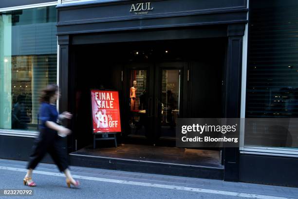 Pedestrian walks past a sale sign at the entrance of a Baroque Japan Ltd. AZUL by moussy store in Osaka, Japan, on Wednesday, July 26, 2017. Japan is...