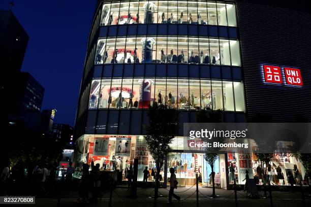 Pedestrians past a Uniqlo store, operated by Fast Retailing Co., illuminated at night in Osaka, Japan, on Wednesday, July 26, 2017. Japan is...