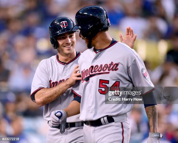 Zach Granite and Ervin Santana of the Minnesota Twins celebrate their runs from a Joe Mauer single to take a 3-0 lead over the Los Angeles Dodgers...