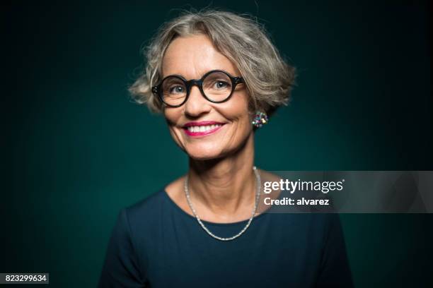 glückliche frau in brillen vor grünem hintergrund - formelles portrait stock-fotos und bilder