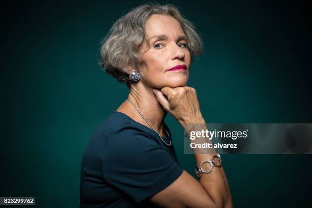 portrait of mature woman with hand on chin - studio portrait of mature woman stock pictures, royalty-free photos & images