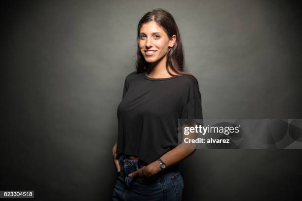 happy young woman standing with hands in pockets - black pants imagens e fotografias de stock