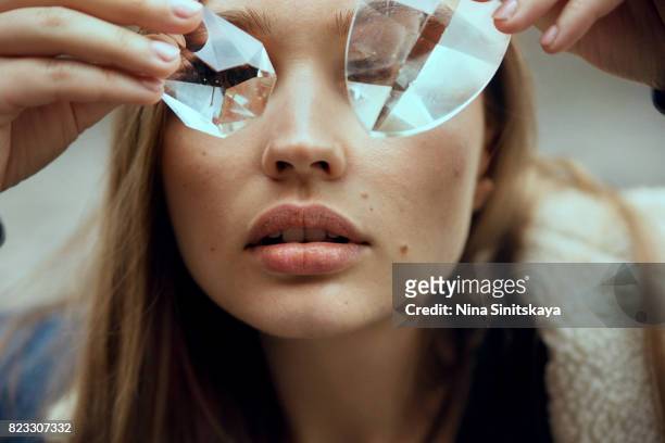 face shot of woman covering eyes with glass crystals - kristallglas stock-fotos und bilder