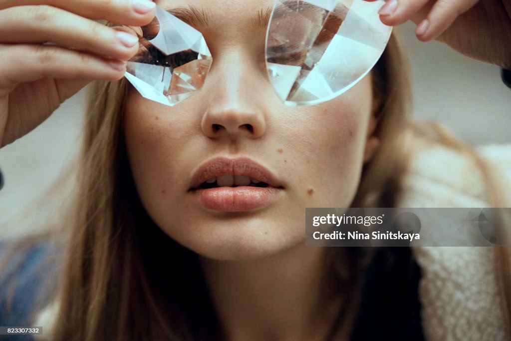 Face shot of woman covering eyes with glass crystals