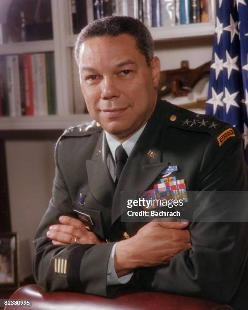 Portrait of American military commander and Chairman of the Joint Chiefs of Staff , General Colin Powell as he leans, arms crossed, on the back of a...