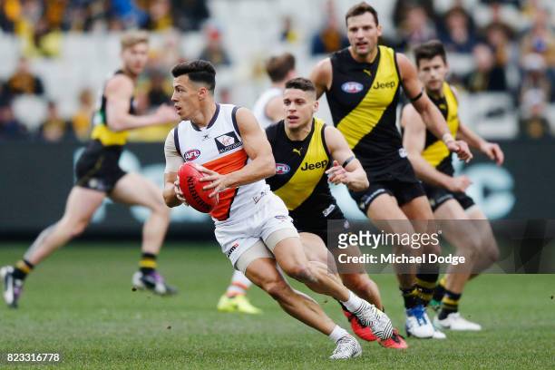 Dylan Shiel of the Giants runs with the ball from Dion Prestia of the Tigers during the round 18 AFL match between the Richmond Tigers and the...
