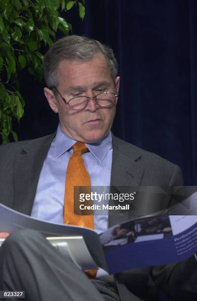 President George W. Bush reads about the Malcolm Baldridge Awards prior to the awards ceremony April 6, 2001 in Alexandria, VA. Prior to his prepared...