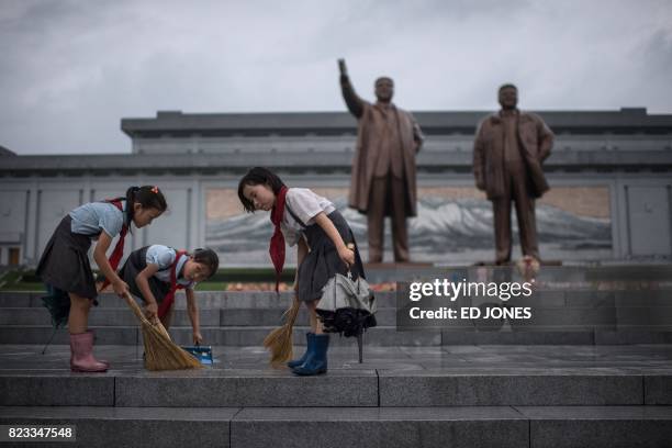 Students clean the steps in front of the statues of late North Korean leaders Kim Il-Sung and Kim Jong-Il at Mansu hill as the country marks 'Victory...