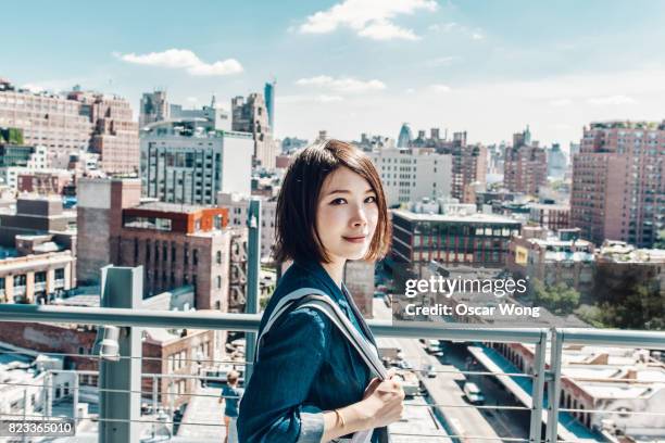 young office lady looking out to new york cityscape, on rooftop - new york vacation rooftop stock pictures, royalty-free photos & images