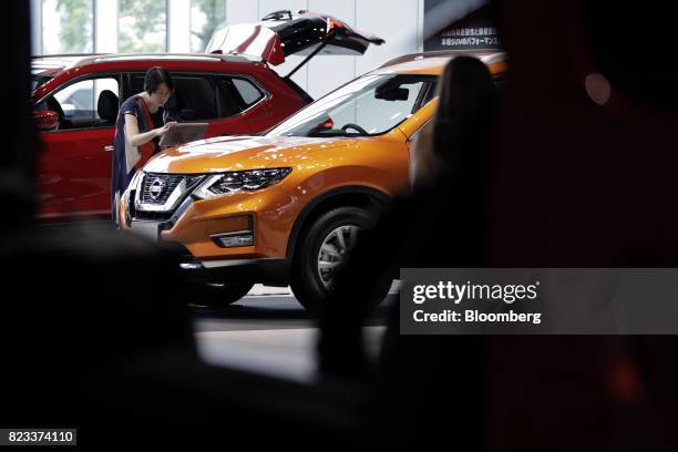 Visitor looks at an information panel for a Nissan Motor Co. X-Trail vehicle at the company's showroom in Yokohama, Japan, on Thursday, July 27,...