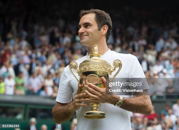 Roger Federer of Switzerland poses for photographs as he celebrates winning the Men's Singles Final against Marin Cilic on day thirteen of the...