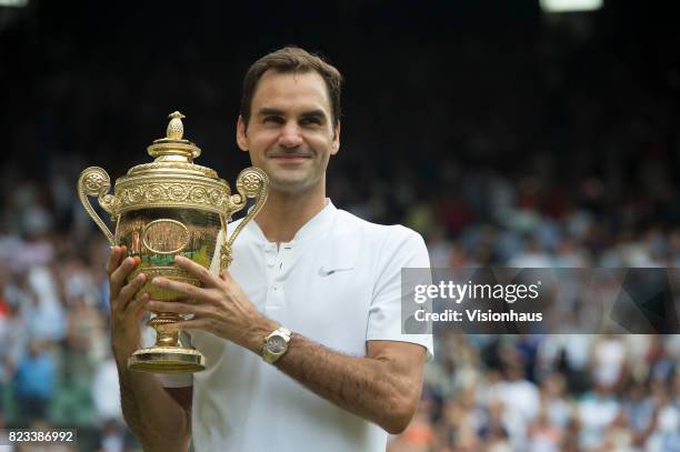 Roger Federer of Switzerland poses for photographs as he celebrates winning the Men's Singles Final against Marin Cilic on day thirteen of the...