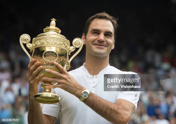 Roger Federer of Switzerland poses for photographs as he celebrates winning the Men's Singles Final against Marin Cilic on day thirteen of the...