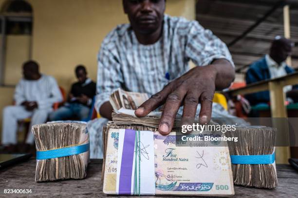 Currency dealer handles bundles of naira banknotes for exchange on the 'black market' in Lagos, Nigeria, on Wednesday, July 26, 2017. Nigeria's...
