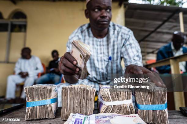 Currency dealer counts bundles of naira banknotes for exchange on the 'black market' in Lagos, Nigeria, on Wednesday, July 26, 2017. Nigeria's...