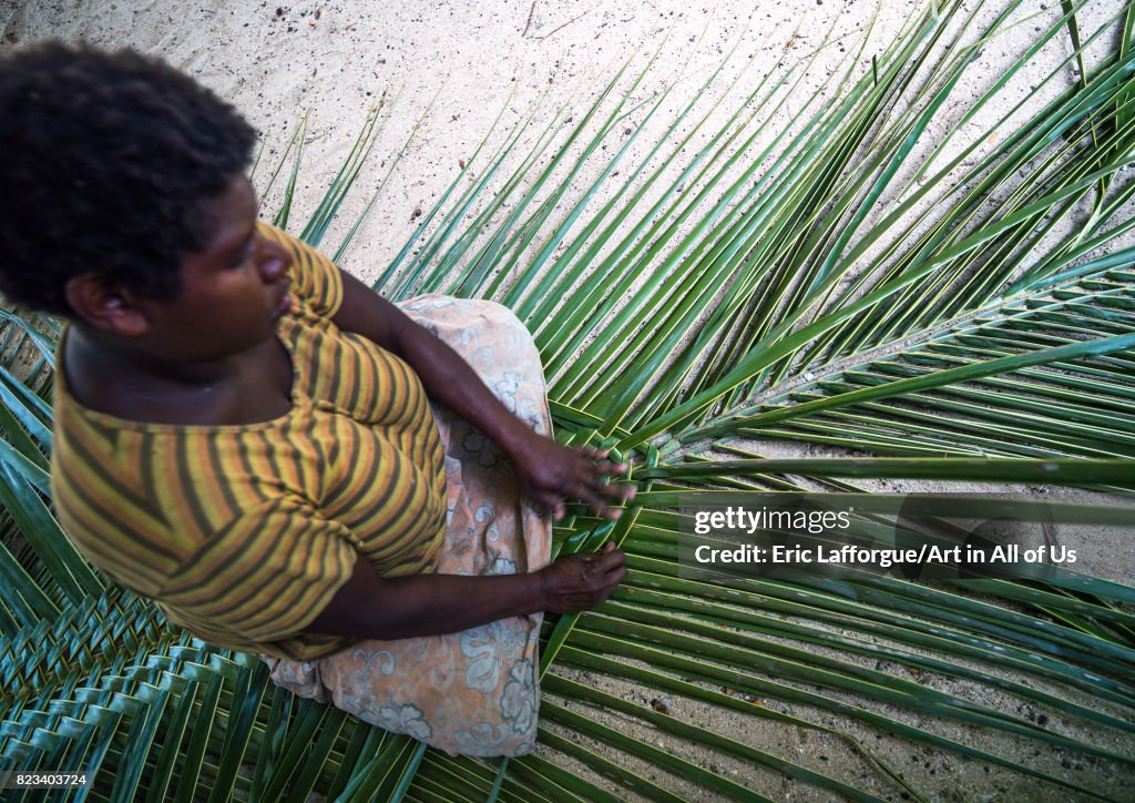 Ni-Vanuatu woman weaving a palm leaf to make a roof, Malekula island, Gortiengser, Vanuatu...