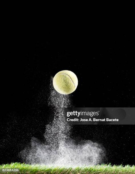 impact and rebound of a ball of tennis on a surface of grass and powder on a black background - ballon rebond stock pictures, royalty-free photos & images