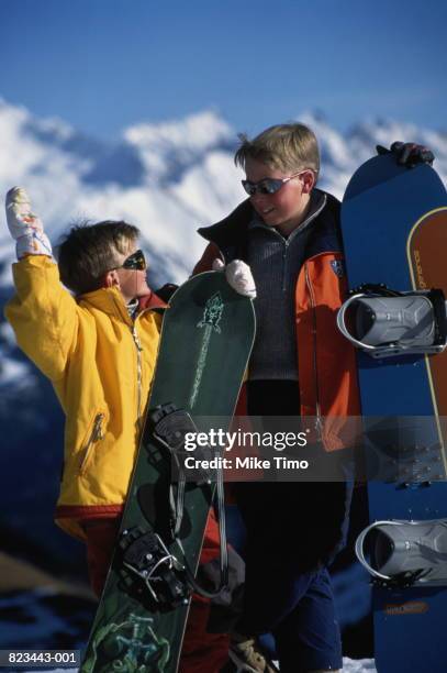 two boys (8-12 years) standing with snowboards in snow, close-up - 12 13 years stock pictures, royalty-free photos & images