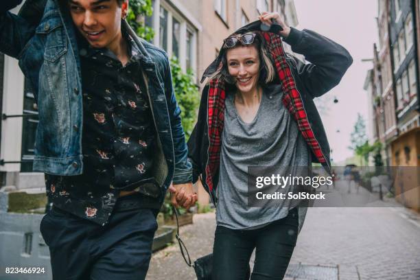 running in the rain in amsterdam - sheltering stock pictures, royalty-free photos & images