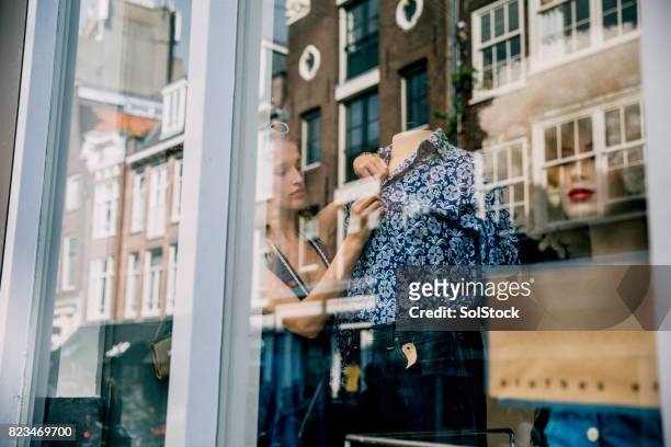 young woman working in a shop window - store window stock pictures, royalty-free photos & images