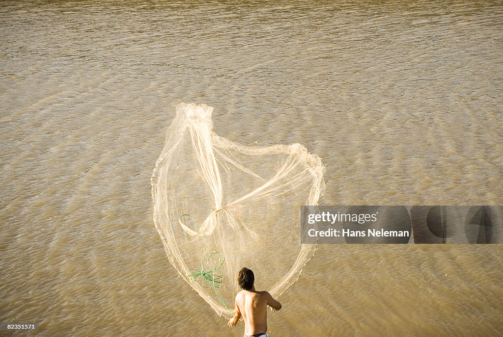 Rear view of a fisherman throwing a fishing net in the sea, Uruguay 