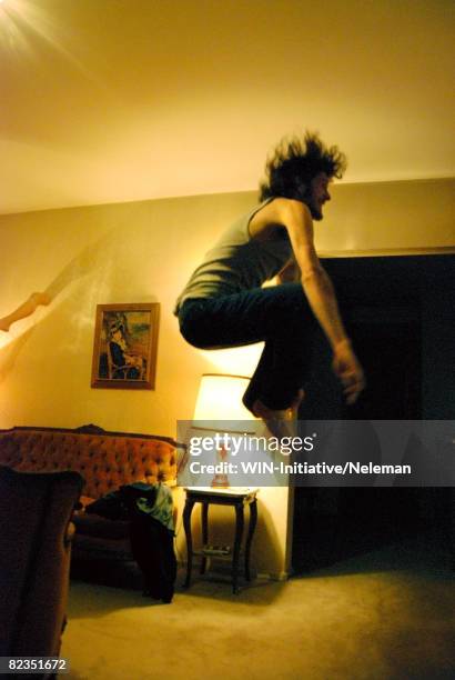 side profile of a young man jumping in a living room, buenos aires, argentina - sports man cave stock pictures, royalty-free photos & images