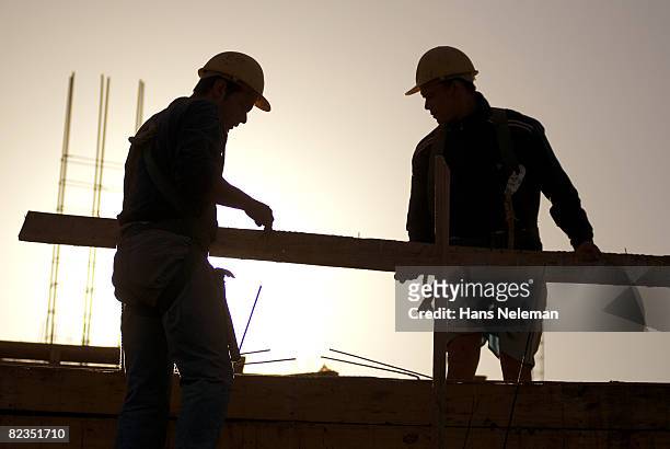 silhouette of two construction workers holding a wooden plank, salto, uruguay - holzbrett himmel stock-fotos und bilder