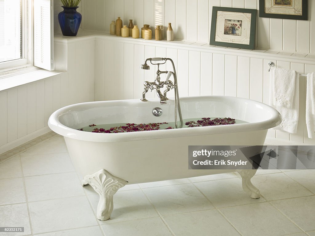A water-filled bathtub with flower petals