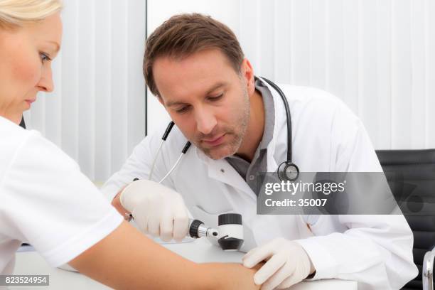 arts doet dermoscopy test met zijn patiënt - dermatologie stockfoto's en -beelden