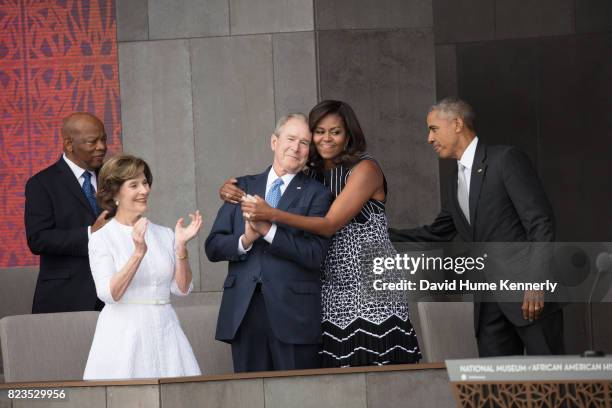 First Lady Michelle Obama hugs former President George W Bush at the opening of the National Museum of African American History and Culture,...
