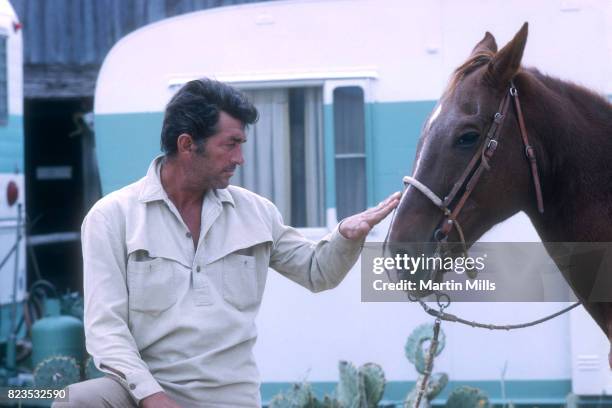 Entertainer Dean Martin pets his horse on the set of the 20th Century Fox film 'Bandolero!' in 1967.
