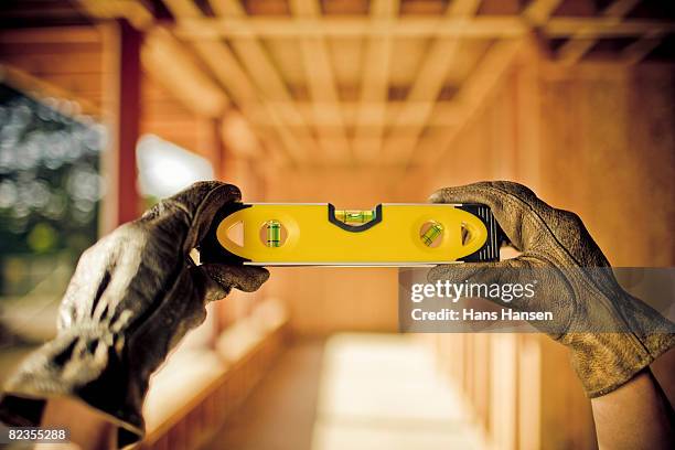 hands holding a level, contruction in background - spirit level stock pictures, royalty-free photos & images