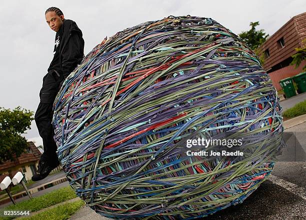 Joel Waul poses for a photograph with the 8,200 pound rubber band ball that he created in the driveway of his home August 14, 2008 in Lauderhill,...