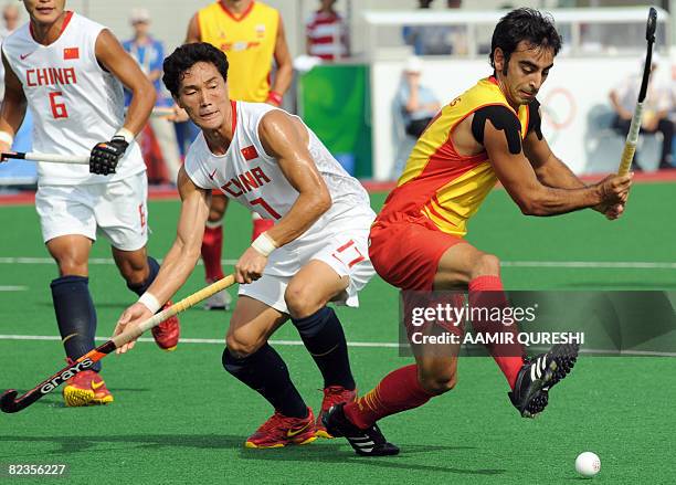 Eduard Arbos of Spain hits the ball as Hu Liang of China defends during their 2008 Beijing Olympic Games men's field hockey match in Beijing on...