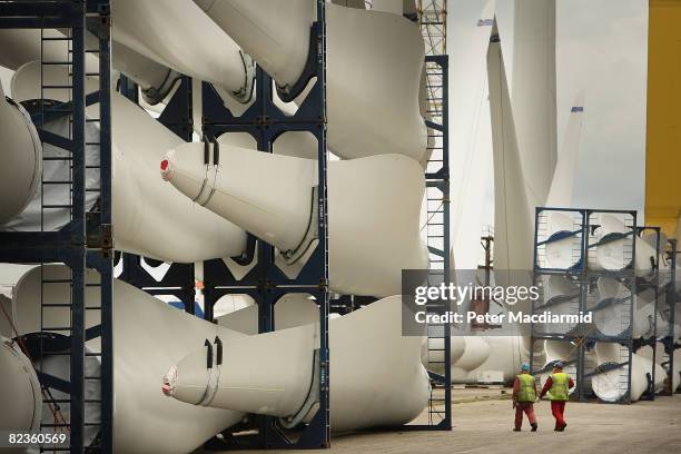 Workers pass stored wind turbine blades at the Harland & Wolff shipyard on August 14, 2008 in Belfast, Northern Ireland. 60 wind turbines are being...