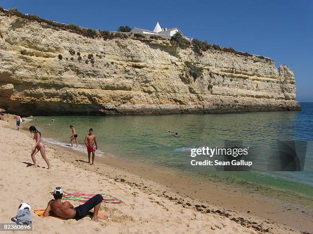 Visitors enjoy a beach on the Algarve coast on July 30, 2008 near Armacao de Pera, Portugal. Portugal is becoming an increasingly popular tourist...