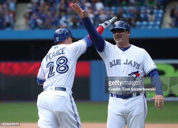 Steve Pearce of the Toronto Blue Jays is congratulated by first base coach Derek Shelton as he rounds the bases after hitting a game-winning grand...