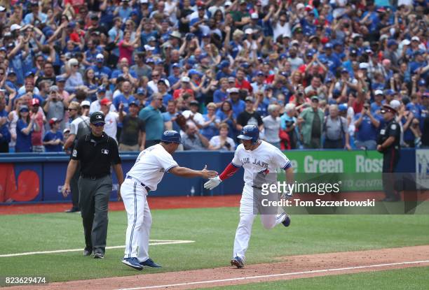Steve Pearce of the Toronto Blue Jays is congratulated by third base coach Luis Rivera as he rounds the bases after hitting a game-winning grand slam...
